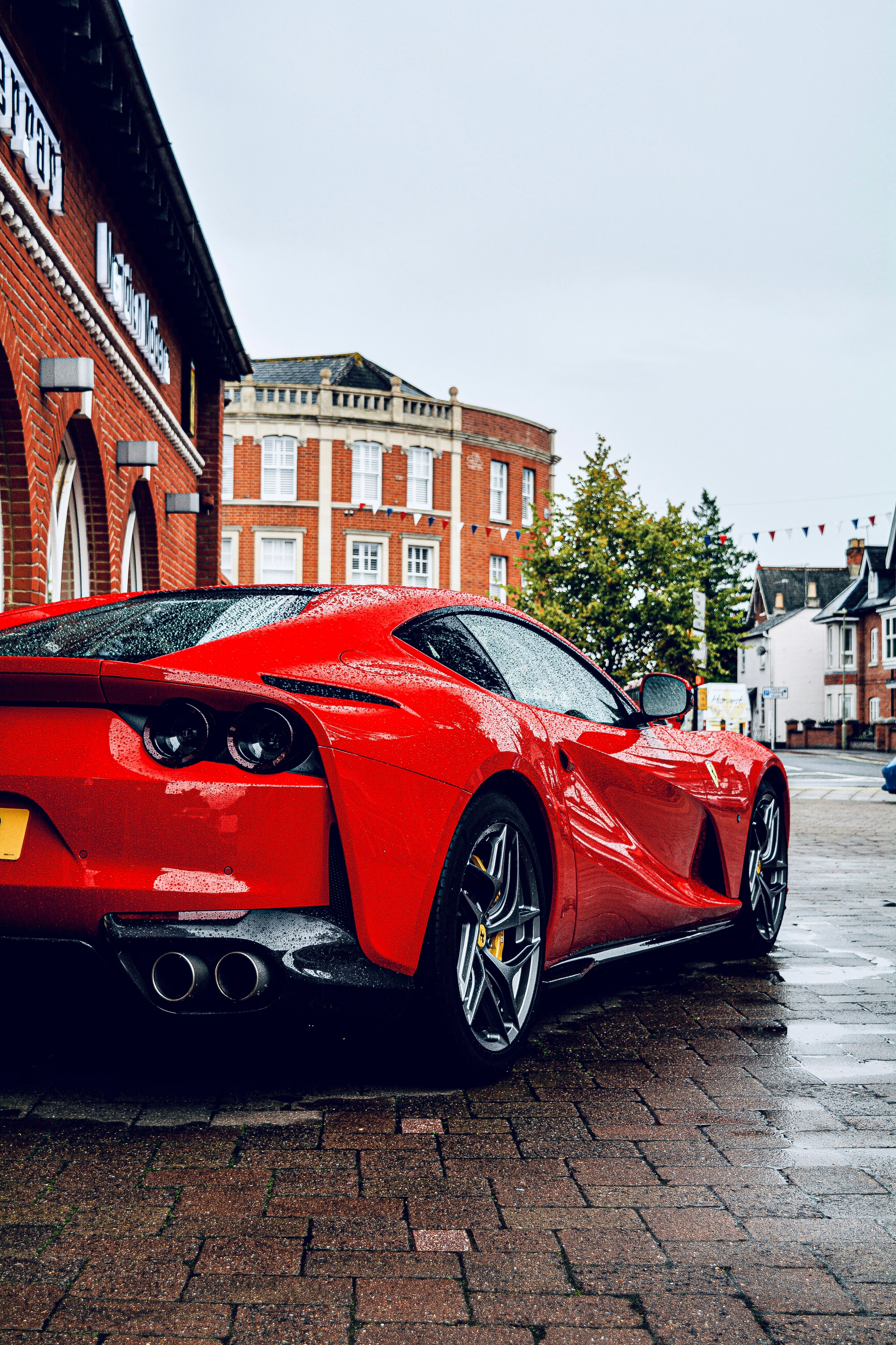 Red Ferrari 812 on a wet brick street