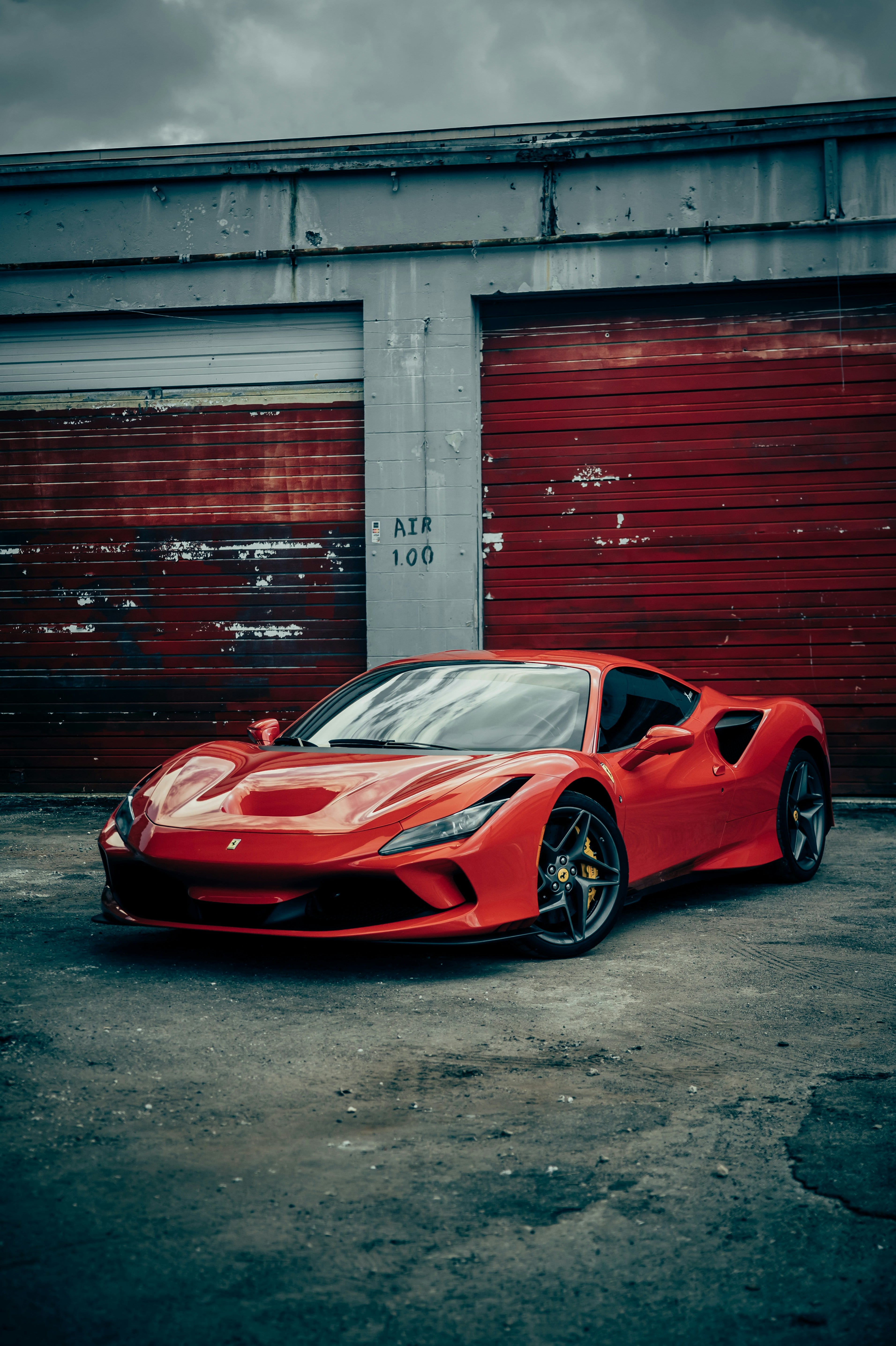 Red Ferrari F8 parked before weathered red garage doors