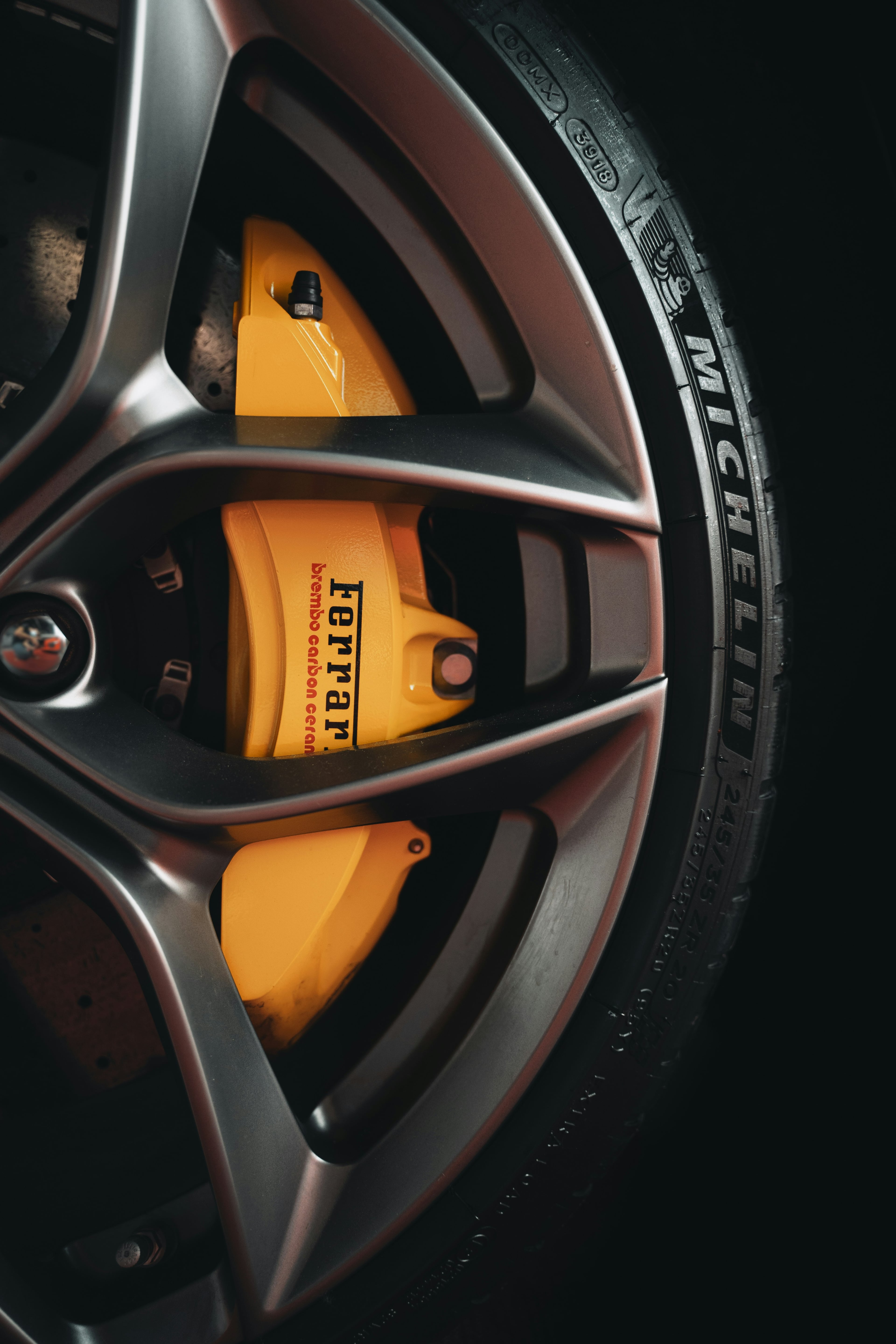Yellow Ferrari brake caliper behind a dark alloy wheel