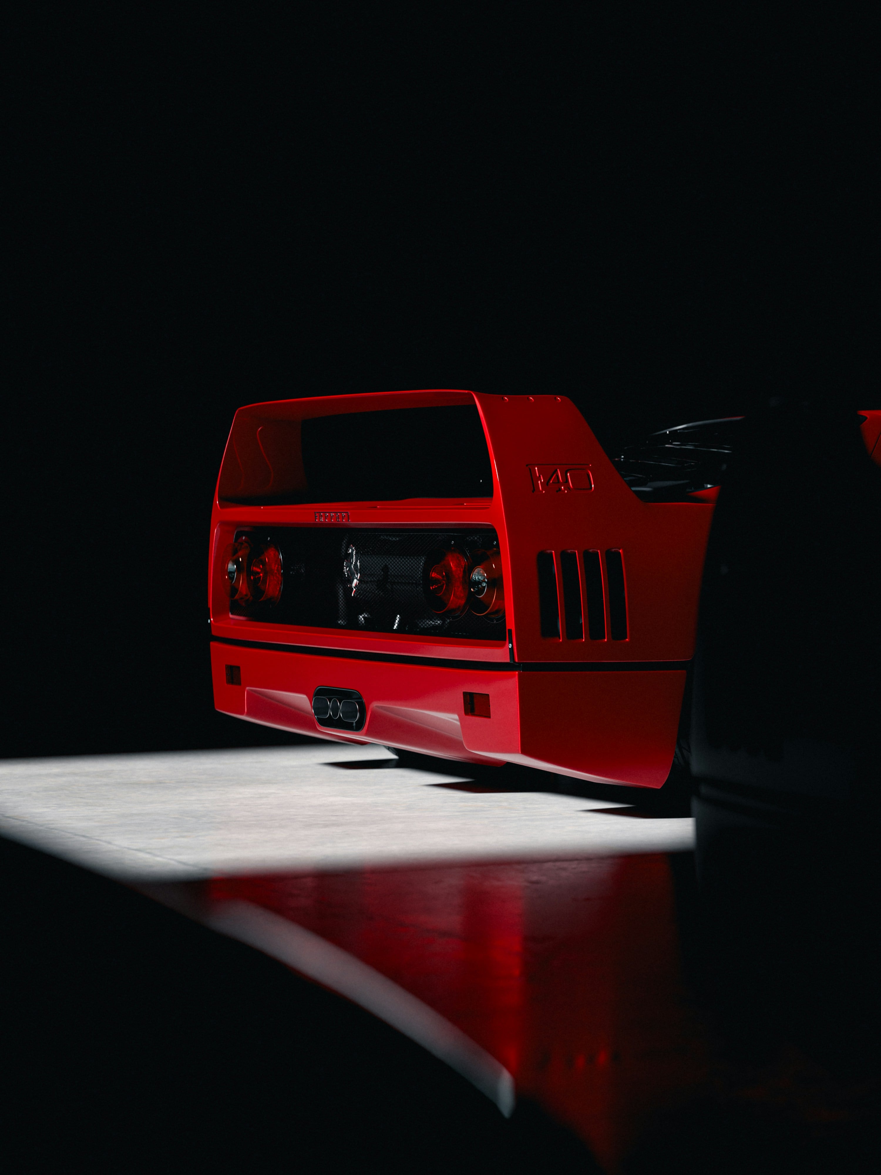 Red Ferrari F40 lit from above in a darkened studio